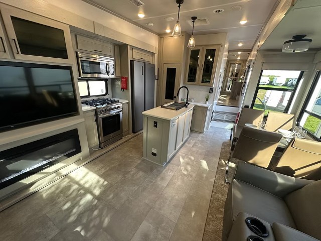 Full kitchen with TV wall and open hallway layout inside fifth wheel unit