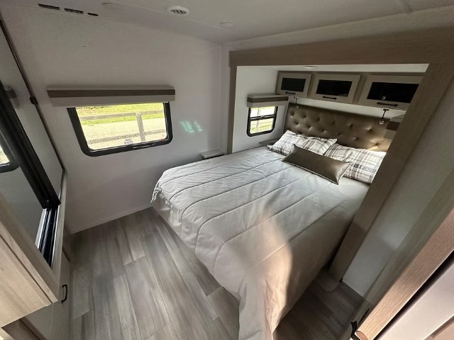 Spacious bedroom with queen bed, upholstered headboard and windows